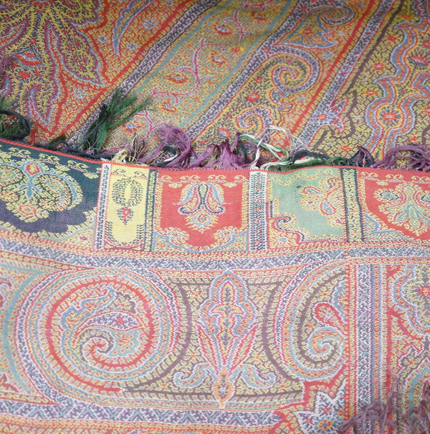 A 19th century woven multi coloured wool and silk Paisley shawl, with large all over paisley tear drop design and brightly coloured fringed borders, 335cm long x 166cm wide